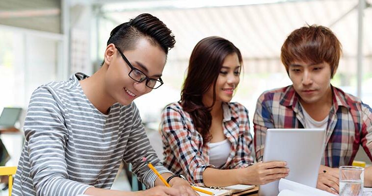 A young woman and two young men studying together.