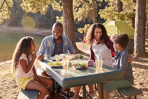 Family Camping By Lake On Hiking Adventure In Forest Central Florida Lifestyle family sitting outside eating in nature in the summer