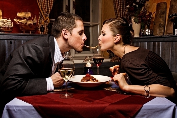 Couple Sharing Single Strand of Pasta at Dinner Central Florida Lifestyle Couple dressed up and sharing a single strand of pasta at a romantic dinner