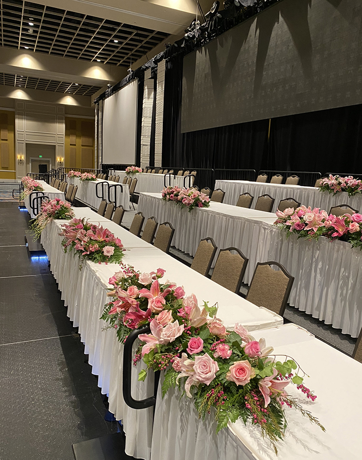 BLOOM-IN-GLORY - Central Florida Lifestyle Three rows of white tables with pink and green flower bouquets and brown chairs.