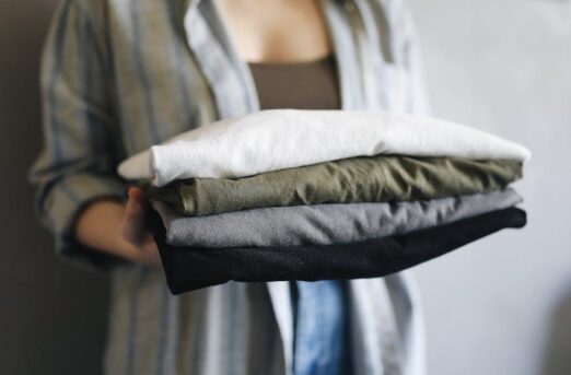 Stack of folded cotton crop tops beside sunglasses and a straw tote